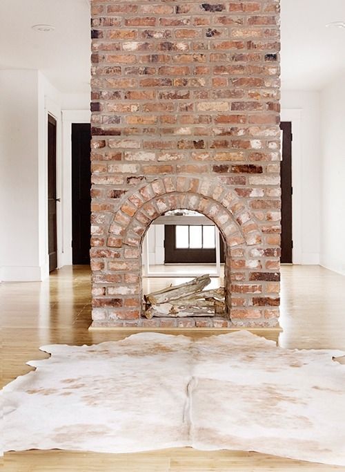 an empty room with a brick fireplace in the center and white carpet on the floor