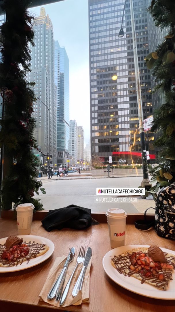 two plates of food sit on a table in front of a window overlooking a city street