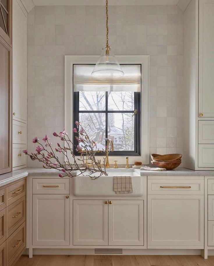 a kitchen with wooden floors and white cabinets, an island sink and window in the center