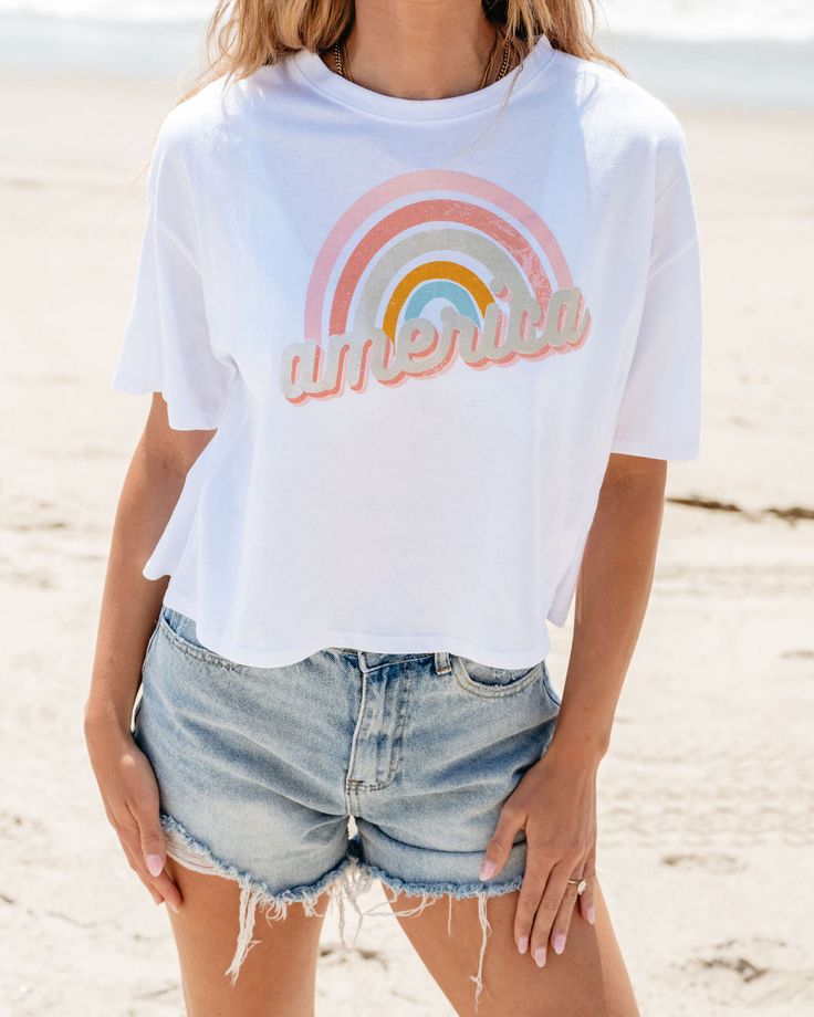 Express your love for America and all the good times you've had over the years by wearing this fun rainbow graphic tee! There's hardly any place that you can't wear it, so go ahead and grab it while you can! All you need to style it with are some denim shorts, multi-color sneakers, and a few other accessories to compliment the look. White Vsco T-shirt With Text Print, Trendy Rainbow Top For Pride, Trendy Rainbow T-shirt For Summer, Trendy Rainbow Summer T-shirt, Trendy Rainbow Print T-shirt For Summer, Trendy Rainbow T-shirt For Pride, Trendy Rainbow Pride T-shirt, Casual Rainbow Pride Tops, Summer Rainbow Graphic Print Tops