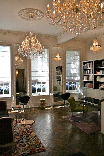 a living room filled with lots of furniture and chandelier hanging from the ceiling