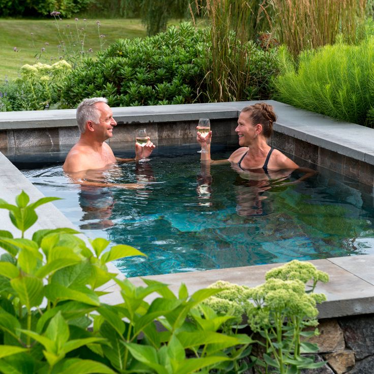 a man and woman are in the pool drinking wine while sitting next to each other