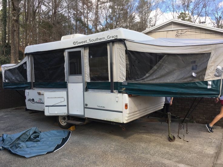 a camper parked in front of a house with tarp on the ground next to it