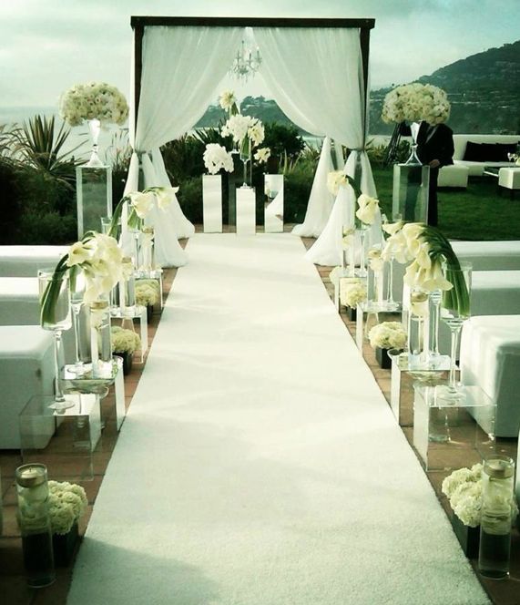 an outdoor wedding setup with white flowers and greenery on the aisle is ready for guests