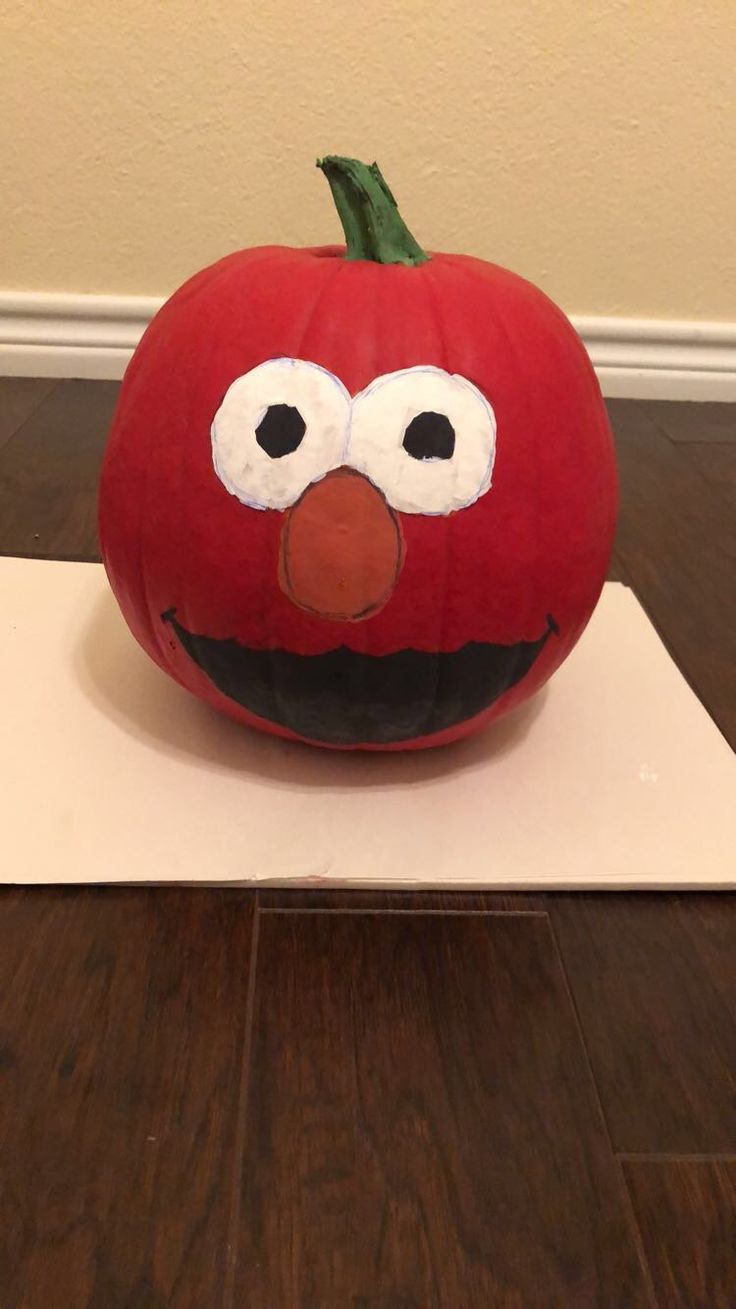 a red pumpkin with an angry bird face on it's head sitting on top of a white board