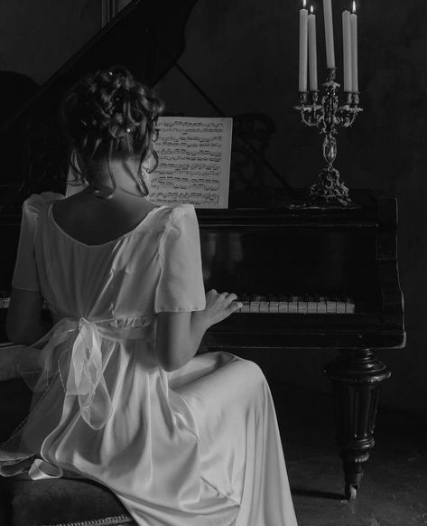 a woman in white dress sitting at a piano