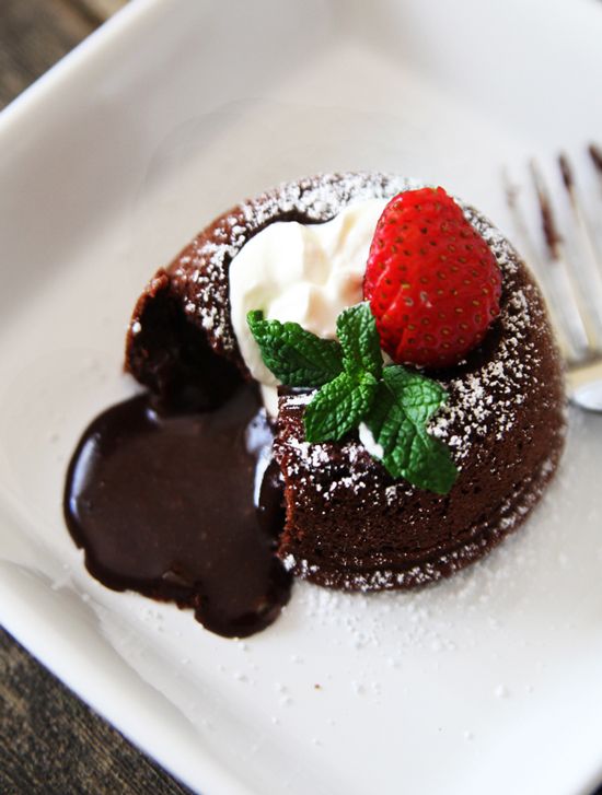 a chocolate dessert with whipped cream and a strawberry on top is sitting on a white plate