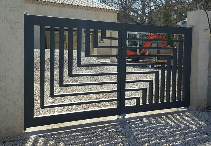 an iron gate is shown in front of a white building with a construction truck behind it