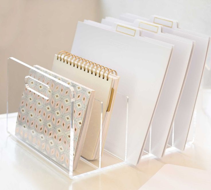 several folders are stacked on top of each other in a clear holder with gold handles