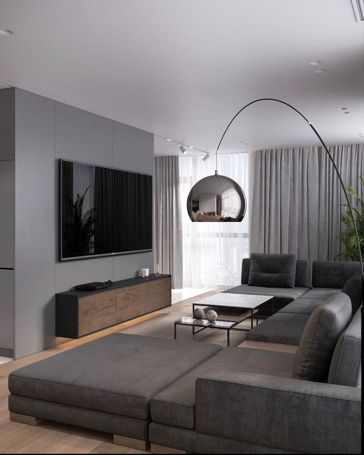 a living room with grey couches and a large flat screen tv mounted on the wall