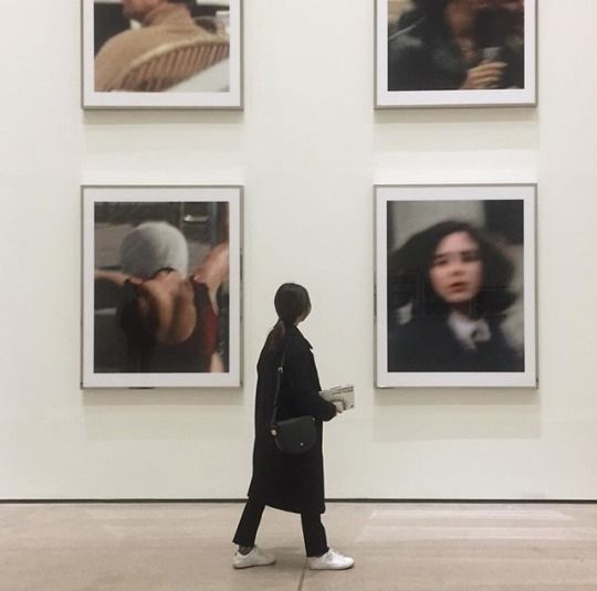 a person walking past some pictures on the wall