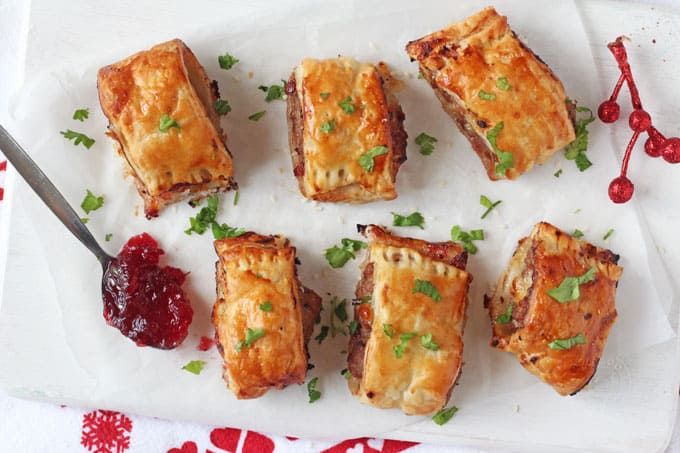 several small pastries on a white plate with cranberry sauce