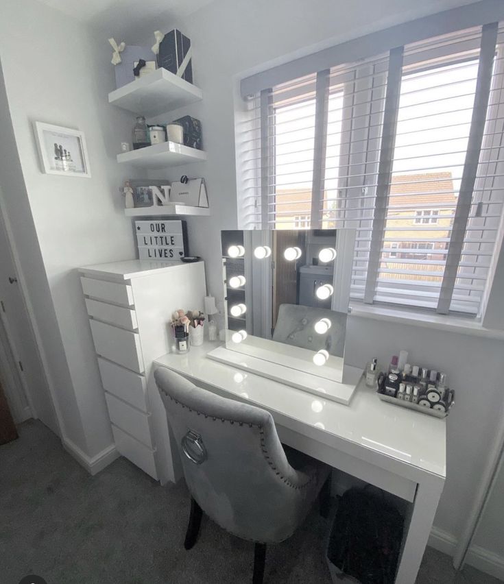 a white desk with lights on it and a chair in front of the mirror,