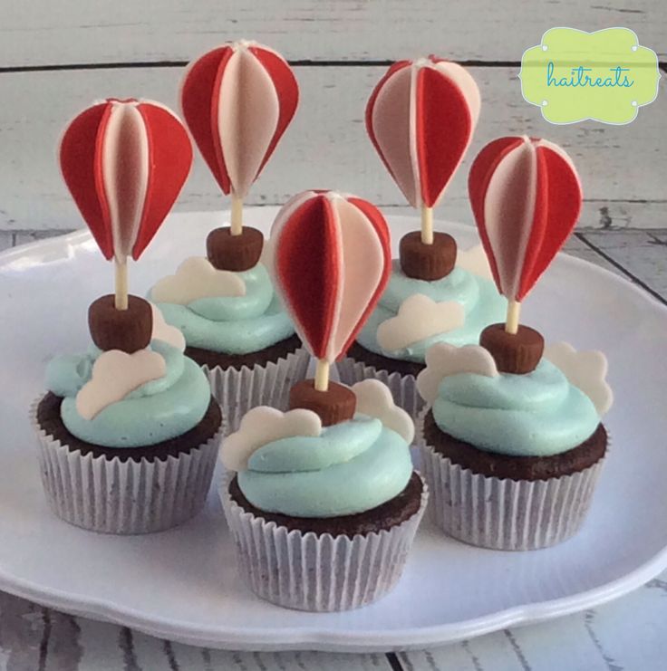 cupcakes with hot air balloons on top are sitting on a white platter