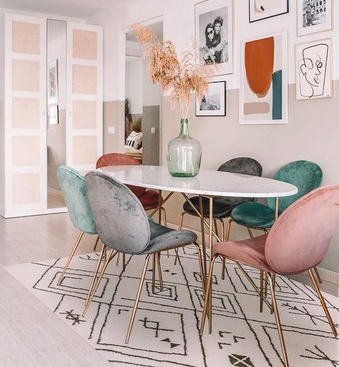 a dining room table with chairs and pictures on the wall behind it in an apartment