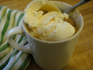 a cup filled with ice cream sitting on top of a wooden table next to a green and white towel