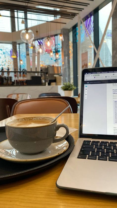 a laptop computer sitting on top of a wooden table next to a cup of coffee