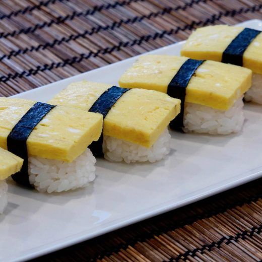 there are pieces of sushi with blue strips on top of it, sitting on a white plate