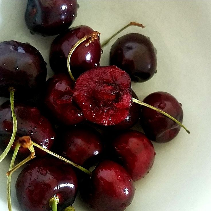 some cherries are in a white bowl on the table and ready to be eaten