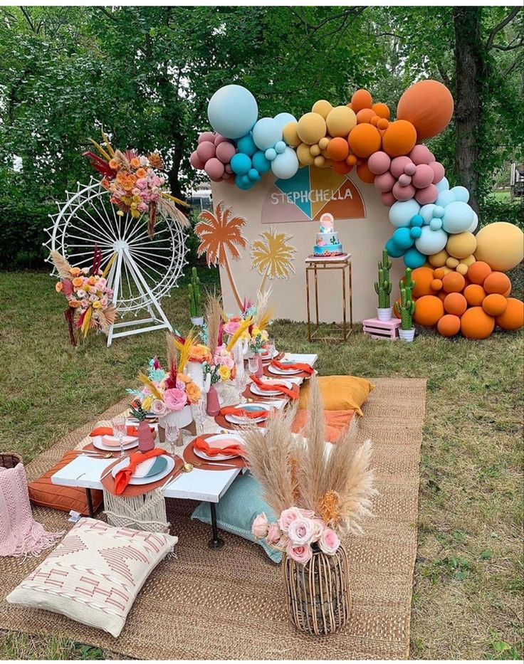 an outdoor party with balloons and decorations on the grass, including plates and napkins