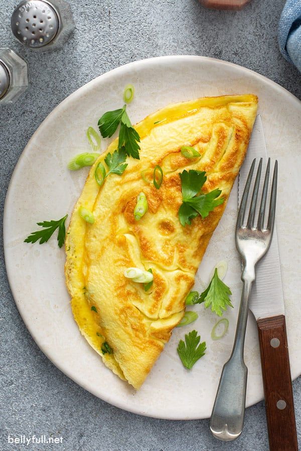 an omelet on a white plate with a fork and knife next to it