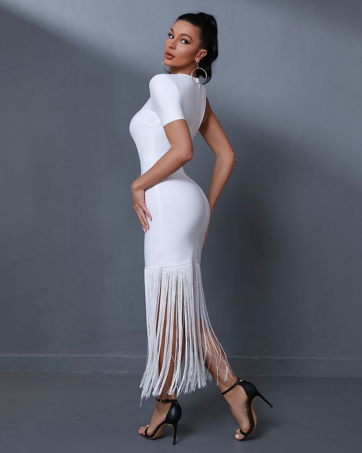 a woman posing in a white dress with fringes on the skirt and high heels