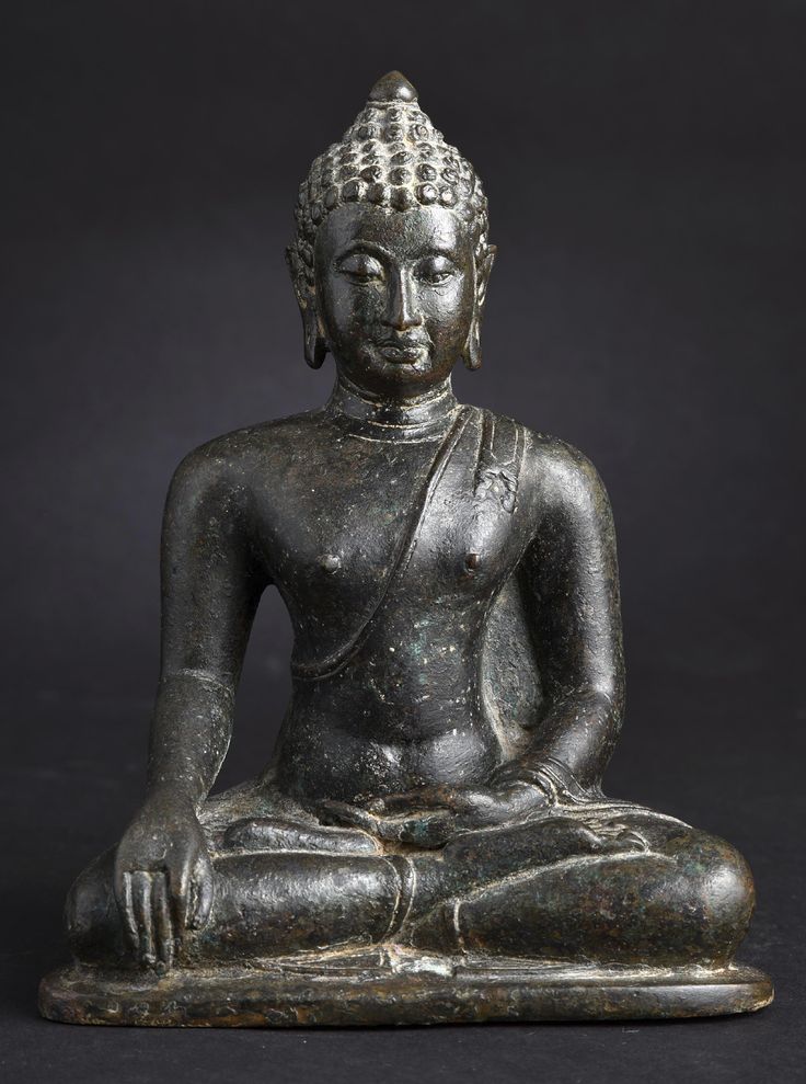 an old buddha statue sitting on top of a black surface