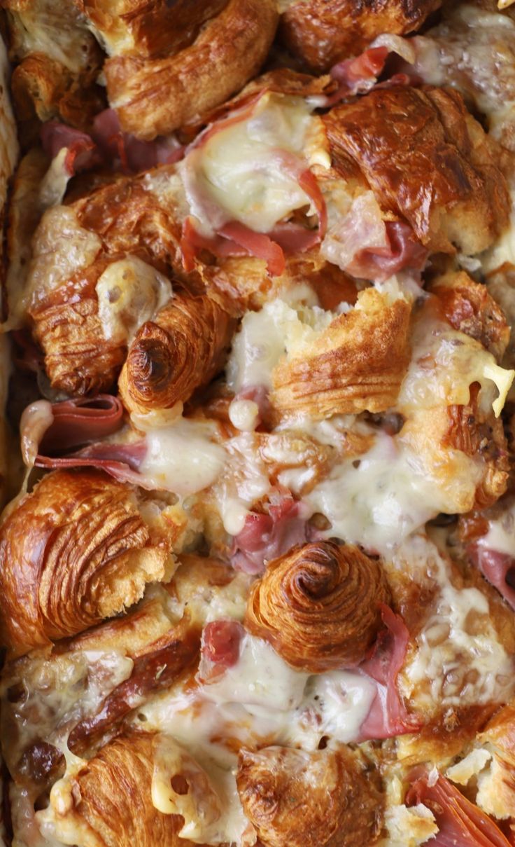 a close up of a pizza covered in cheese and meats on top of it