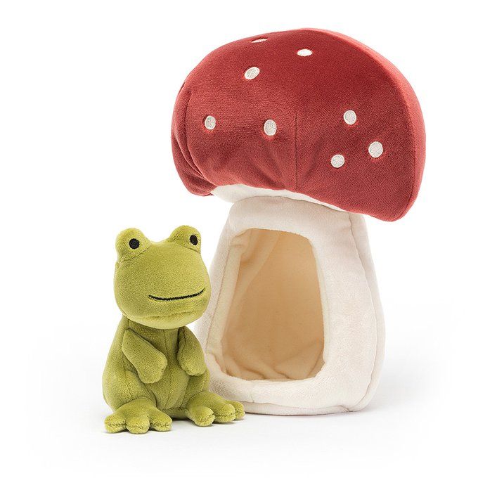 a stuffed frog sitting next to a mushroom shaped house