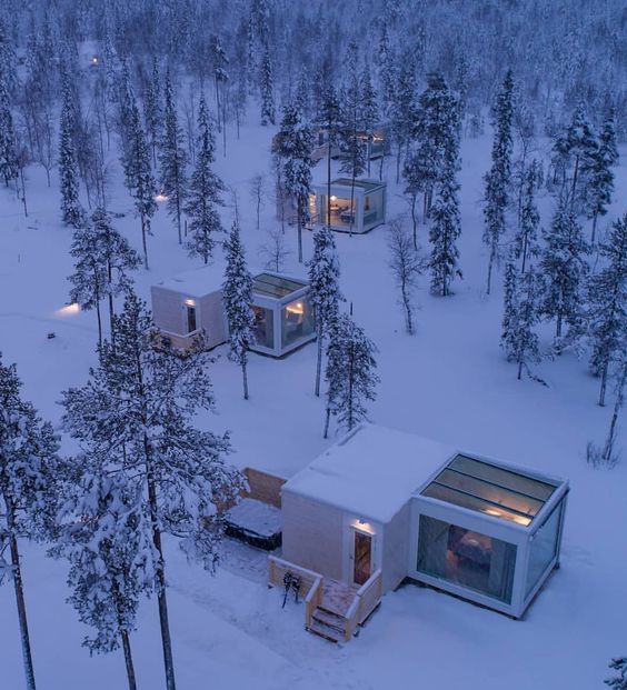 small cabins in the snow surrounded by trees and lights at night, as seen from above