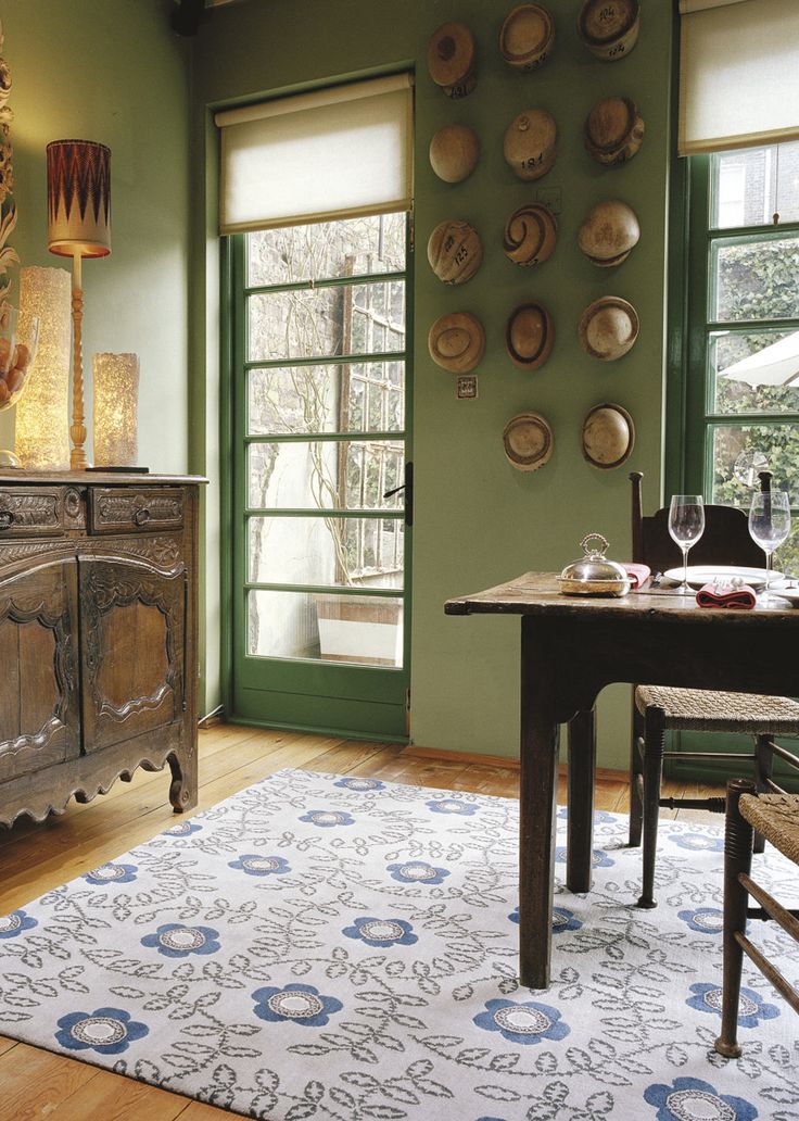 a dining room with green walls and wooden furniture, plates on the wall above a table