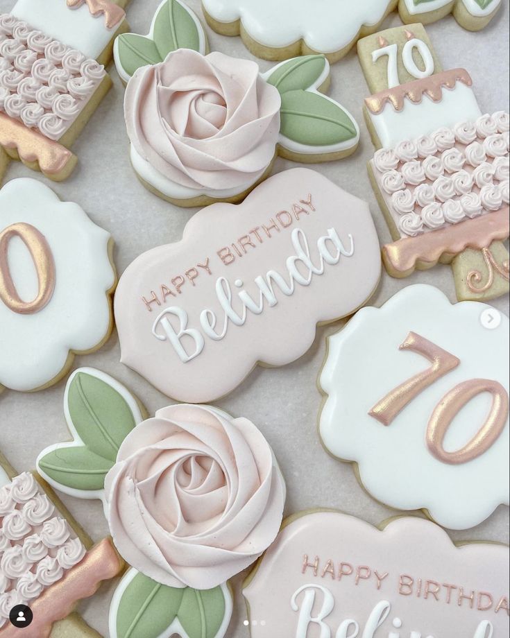 decorated cookies with pink and gold icing are displayed on a white tablecloth that says happy birthday