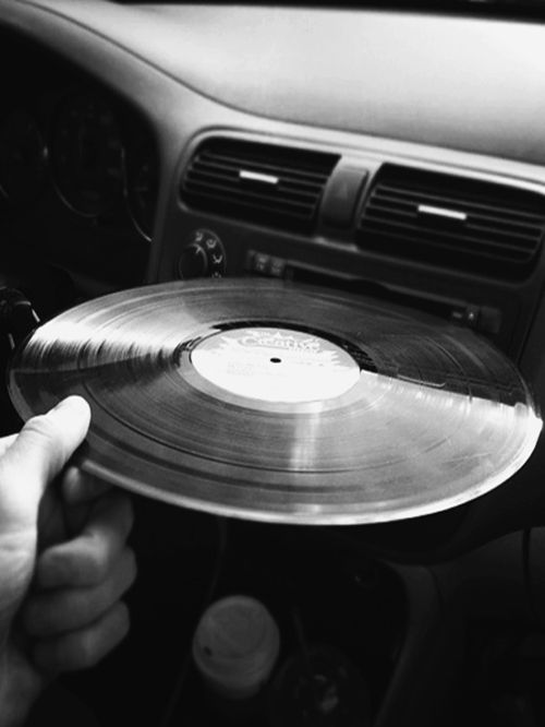 a person holding a record in their hand while sitting in the driver's seat of a car