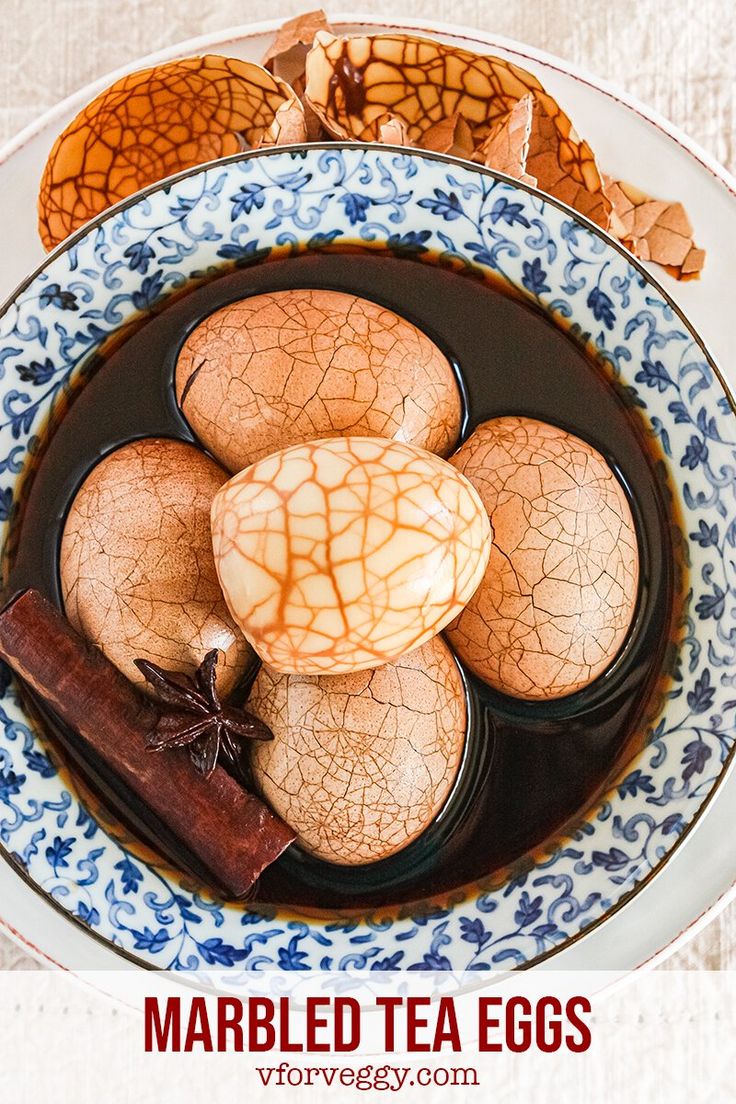 marbled tea eggs in a blue and white bowl with cinnamon stick on the side