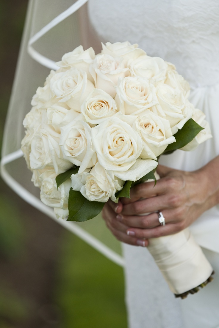 a bride holding a bouquet of white roses