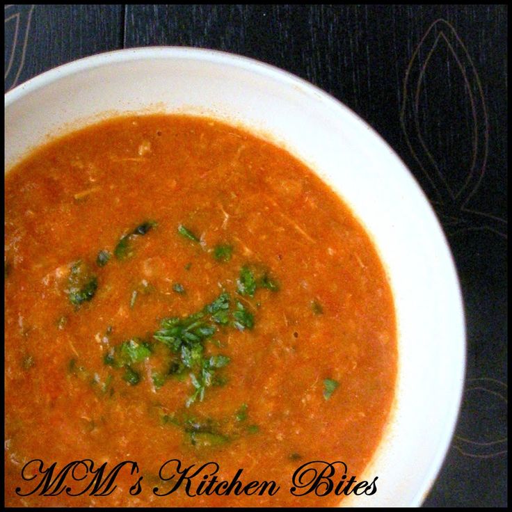 a white bowl filled with red soup and garnished with parsley on top