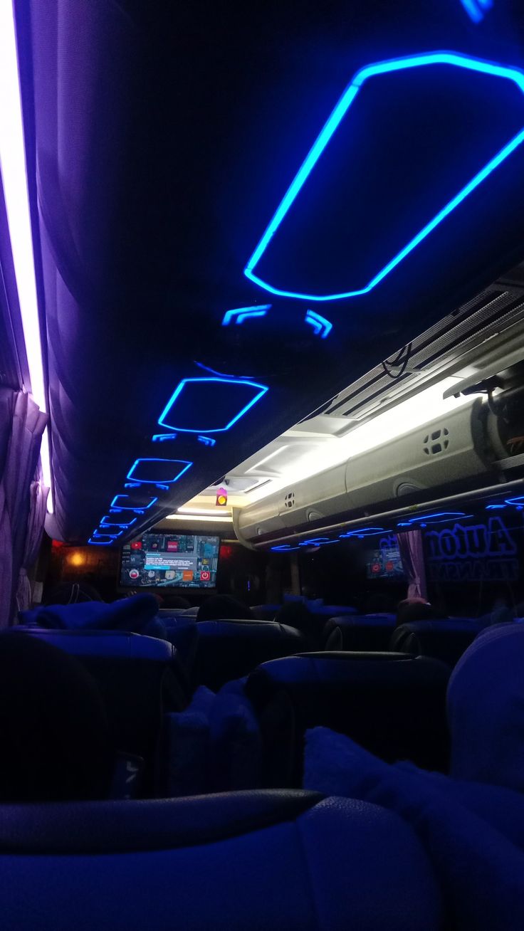 the inside of an airplane with blue lights on it's ceiling and seats down