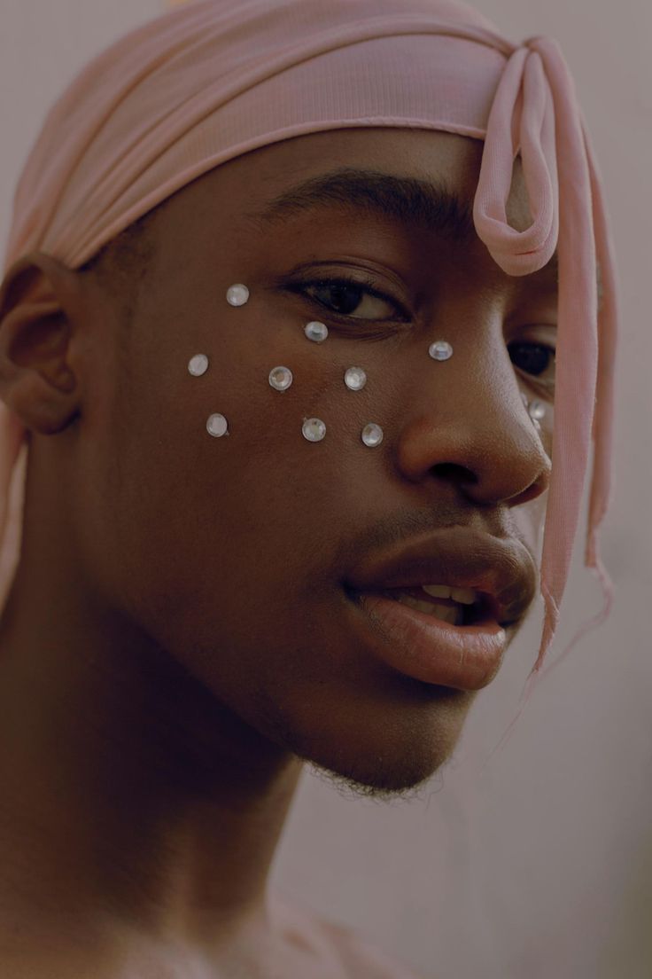 a young man with white dots on his face and pink turban over his head