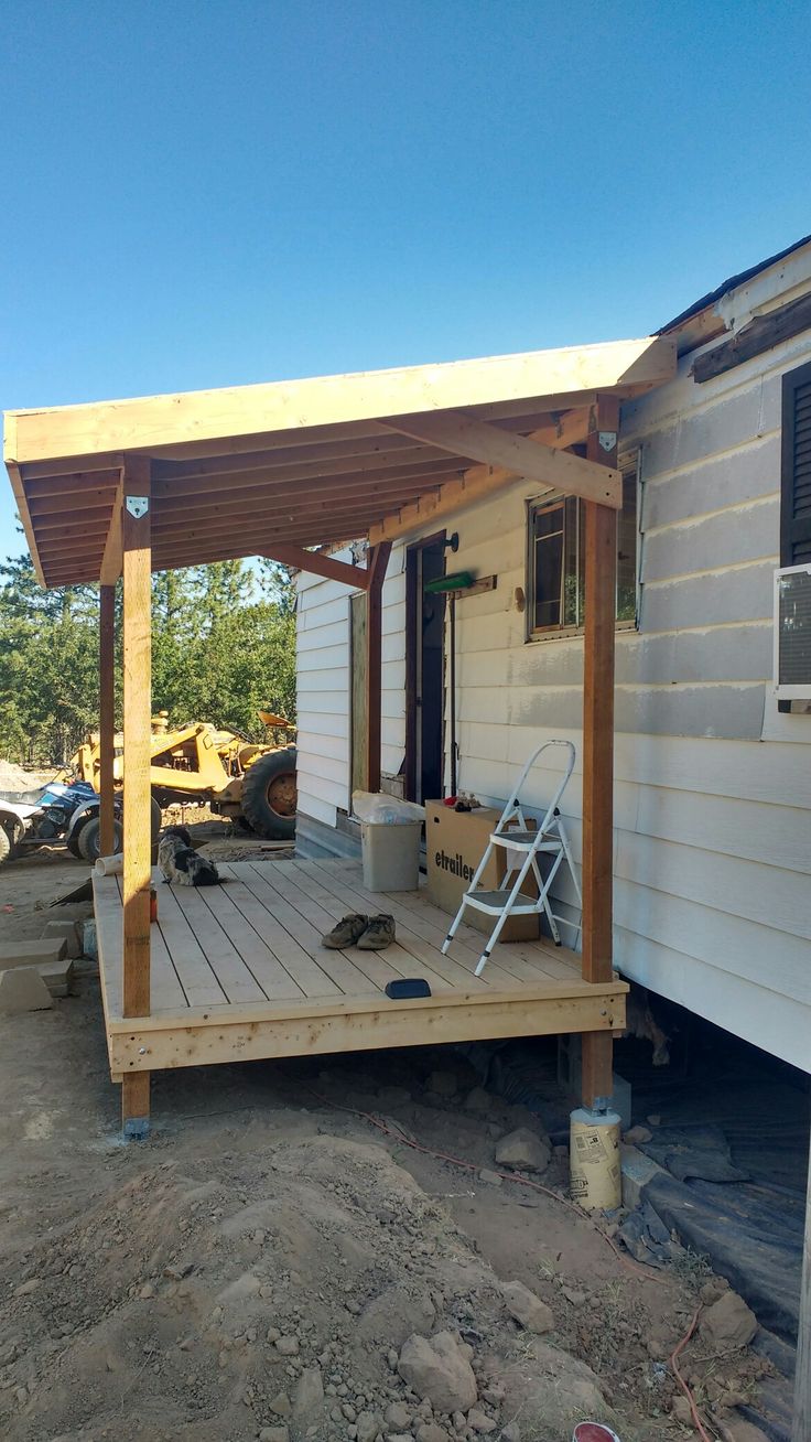 a small white house with a wooden deck and covered porch in the middle of it