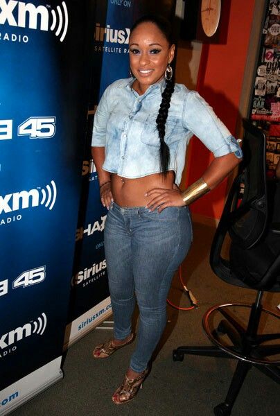 a woman standing in front of a radio booth with her hands on her hips and smiling at the camera