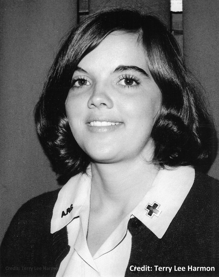 a black and white photo of a woman with short hair wearing a cross on her collar