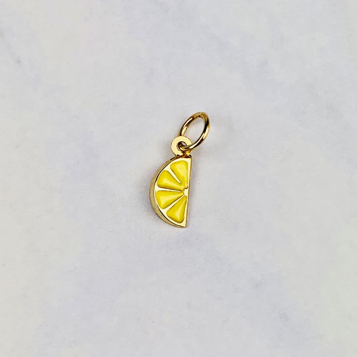 "A beautiful 14K yellow gold 3D Lemon slice pendant charm with baked yellow enamel. It has a soldered ring to attach to a bracelet or a necklace. The very delicate pendant measures 7mm tall by 4mm wide. It can be used as a necklace pendant or a bracelet charm and would make a perfect gift. The pendant can be paired with a shiny 14K Yellow Gold 1.2mm cable link chain in either 16\" or 18\" length or with a 16\" 14K gold-plated cable link chain. All items are packaged ready to be gifted. Unless re Yellow Gold Enamel Round Pendant Charm Necklace, Handmade Yellow Gold Pendant Charms, Gold Enamel Round Pendant Charms, Dainty Yellow Gold Charms With Lobster Clasp, Handmade Yellow Gold Enamel Jewelry, Nickel Free Enamel Pendant Charms, Enamel Round Pendant Charms For Gifts, Enamel Charm Pendant Jewelry, Nickel-free Enamel Pendant Charms