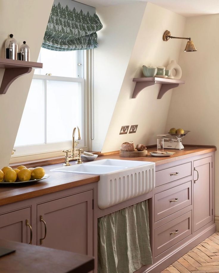 a kitchen with two sinks and some shelves on the wall next to it's windows