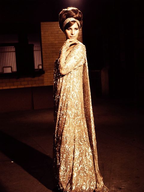 a woman in a gold dress and headdress standing on the street at night