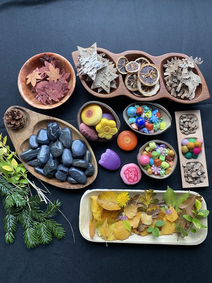 several bowls and trays filled with different types of rocks, leaves, and candy