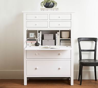 a white desk with two chairs and a plant on top is next to a black chair