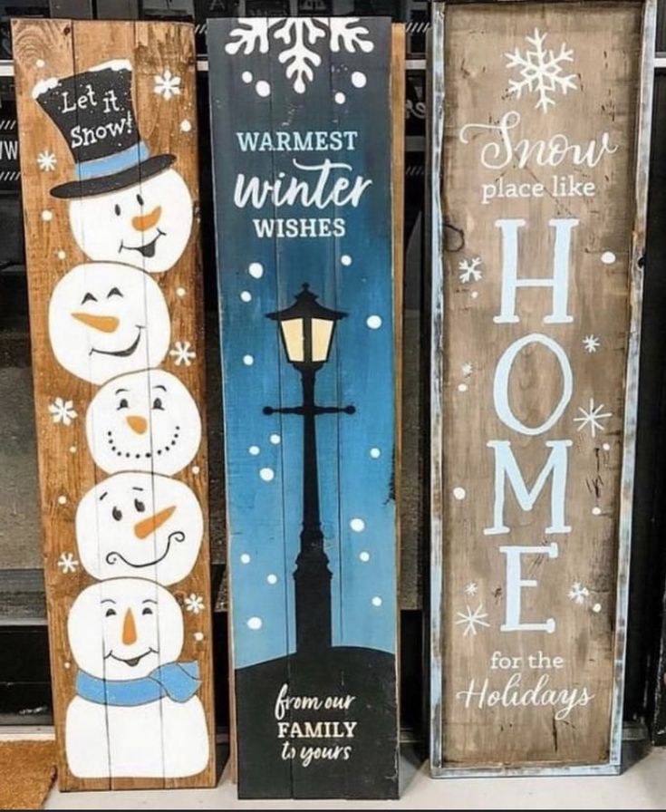 three wooden signs with snowmen on them