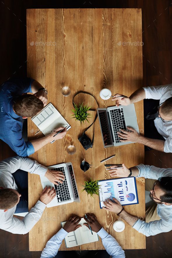 four people sitting at a table with laptops and papers in their hands - stock photo - images