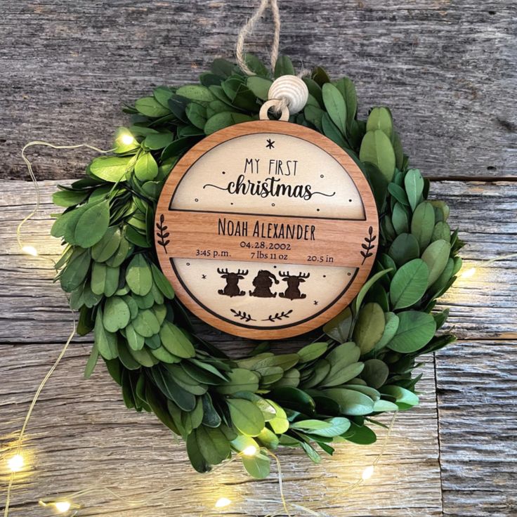 a christmas ornament hanging on a wooden wall with greenery and lights around it