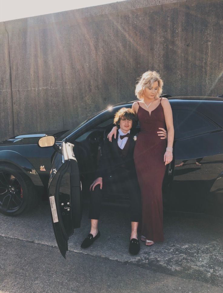 a man and woman standing next to a car